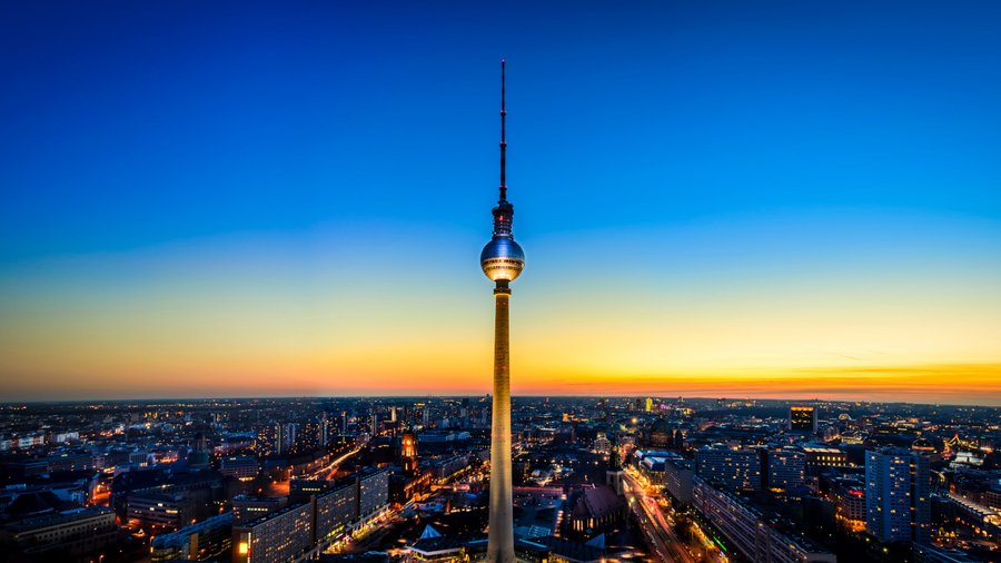 Blick auf Berliner Fernsehturm vor orange-blauem Himmel.